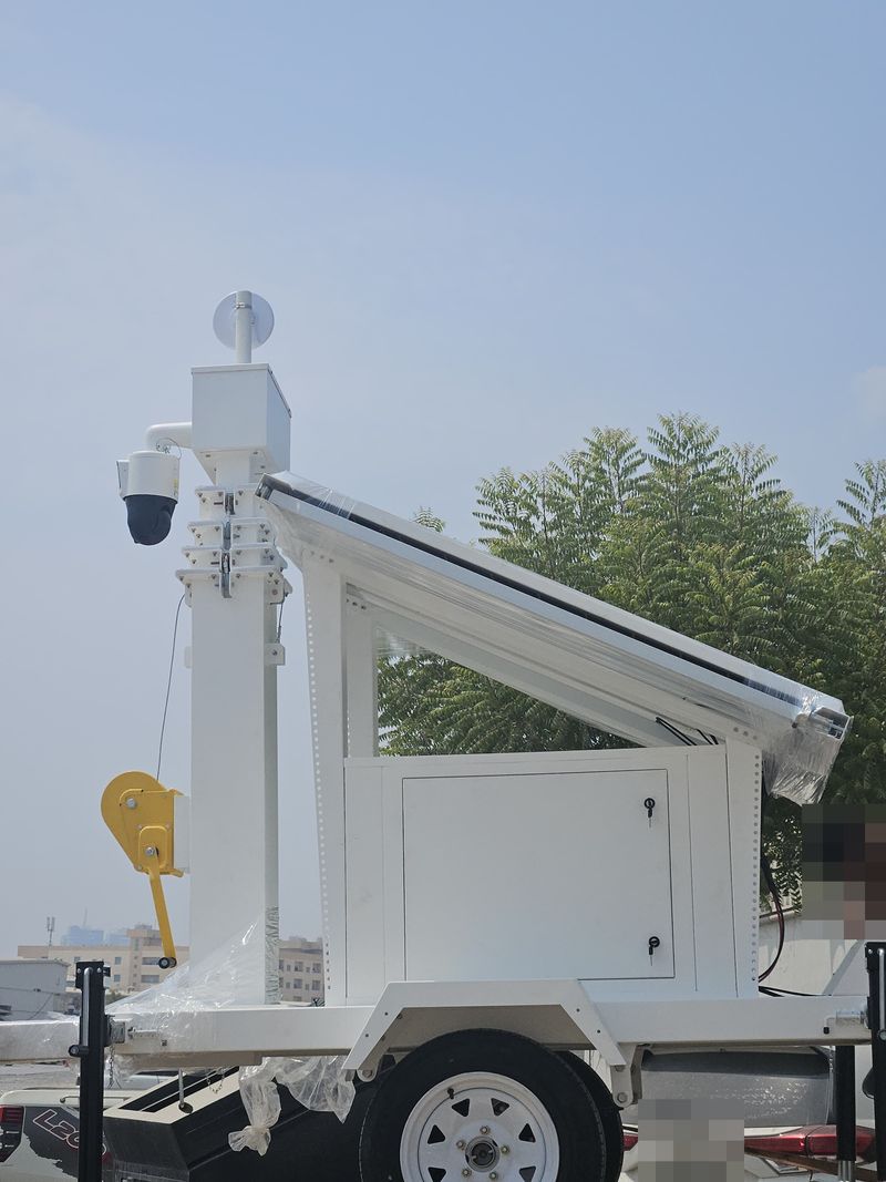 Side view of a solar CCTV trolley showing the tilted solar panel, lockable equipment cabinet and hand-winch mast